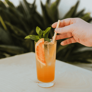 A Jumbo HAY! Straw in a fruit, iced drink with a male hand reaching for the straw