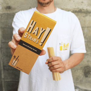Man holding a pack of HAY! straws, compostable drinking straws.