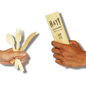 HAY Bamboo Cutlery About Page, images shows two hands, one holding unwrapped HAY Bamboo Cutlery and  the other holding a packed piece of cutlery