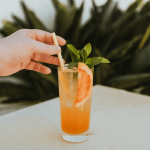 HAY! Straws wider Jumbo straw is shown in a cocktail with a mans hand reaching for it.