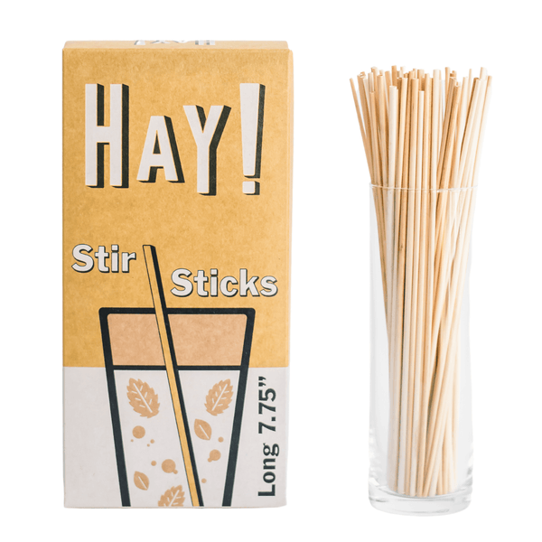 HAY! Stir Sticks displayed in tall glass. Our stirrers are perfect for stirring your favorite hot drink or iced beverage. Available in two sizes, long 7.75" and short 5". They're made from natural wheat stems and tested as gluten-free. Never soggy and 100% compostable. Available in three package quantities: 500 stir stick boxes, 1500 stir sticks and full cases of 3000 Stir sticks.