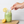 Green smoothie in a jar with a lemon slice on a wooden board and a woman's hand holding a plastic-free HAY! straw made from reed stems and looking like a bamboo straw