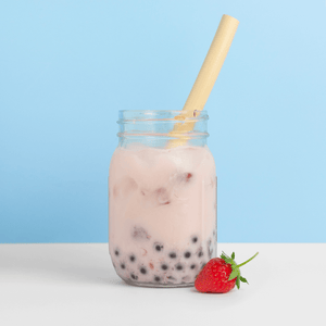 HAY! Straws Boba straw made from reed plant stems in a milk tea with a blue background and a strawberry garnish 